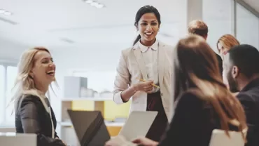 Group of professionals in a meeting, smiling and interacting.