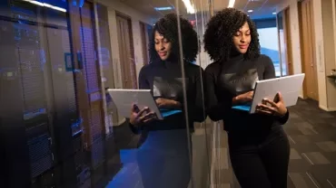 Woman in a data center hallway looking at a tablet computer.