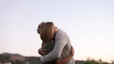 Two people embracing outdoors during sunset.