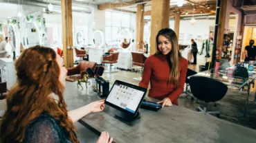 Smiling woman at a retail desk assisting a customer in a modern store.