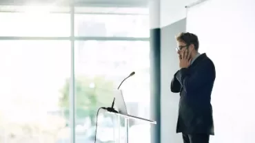 Man at podium looks stressed during a presentation.