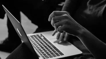 Person typing on a laptop, monochrome setting.