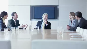 Five business people in a conference room having a discussion.