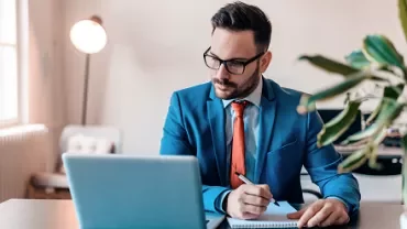 Man in blue suit working on laptop at a desk