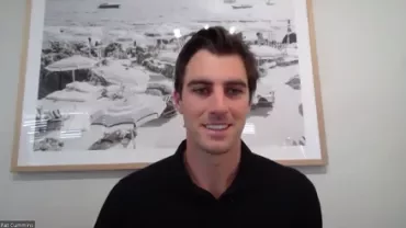 Person smiling in front of a seaside painting in a room.