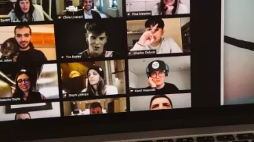 A virtual meeting with multiple participants displayed in a grid on a laptop screen.