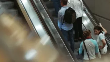 People going up and down on parallel escalators in a busy station.