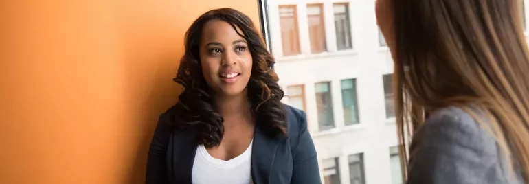 Two women having a conversation in an office setting.