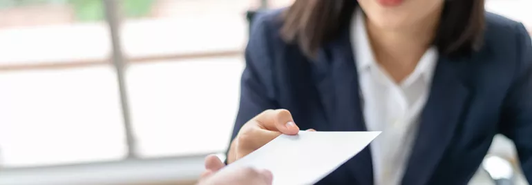 A woman hands over a business card with a smile.