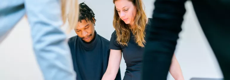Two people collaborating at a table with focus on documents.
