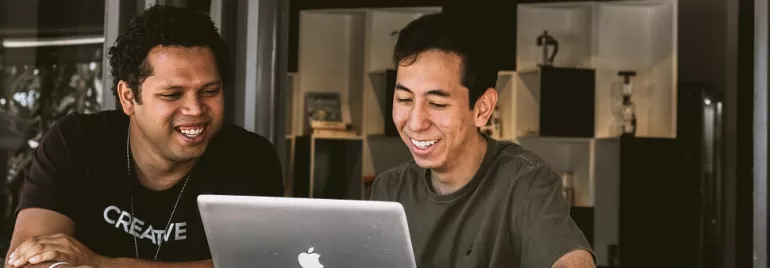 Two people smiling and looking at a laptop screen.