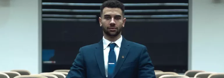 Man in a suit sitting alone in an empty lecture hall.