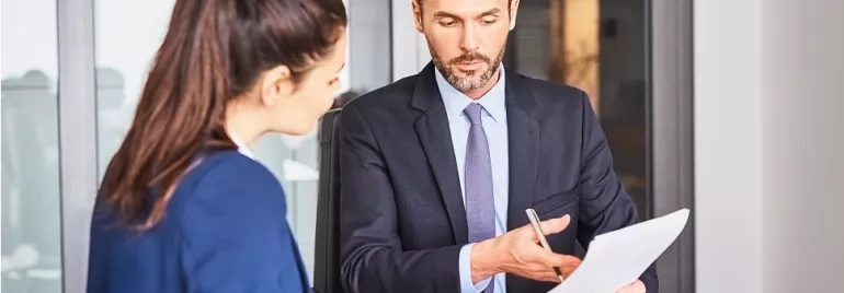 Two professionals reviewing a document in an office setting.