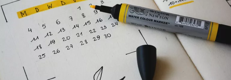A pen next to a hand-drawn calendar on a notepad.