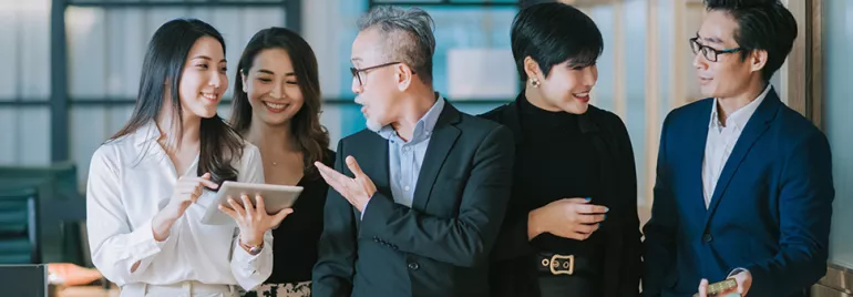 Group of five professionals discussing with a tablet in an office setting.