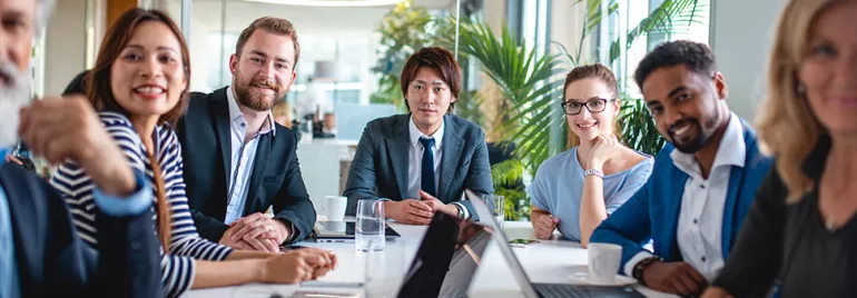 Diverse colleagues in a modern office meeting around a table.