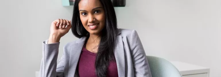 Smiling woman in a gray blazer sitting in a chair.
