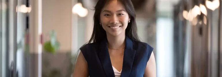 A woman smiling in an office hallway.