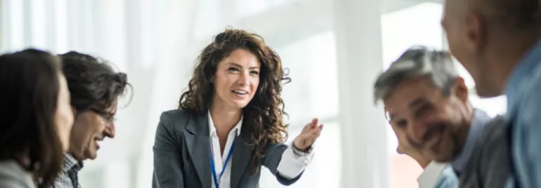 Woman in a suit speaking to a group during a meeting.