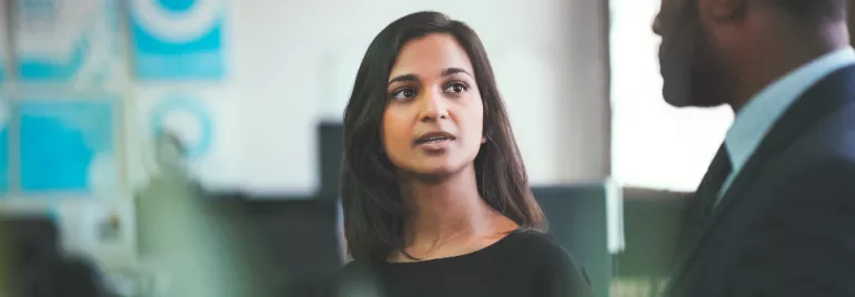 Woman speaking to a man in a business setting.