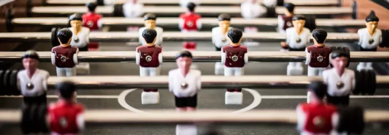 Close-up view of a foosball table with red and white player figures.