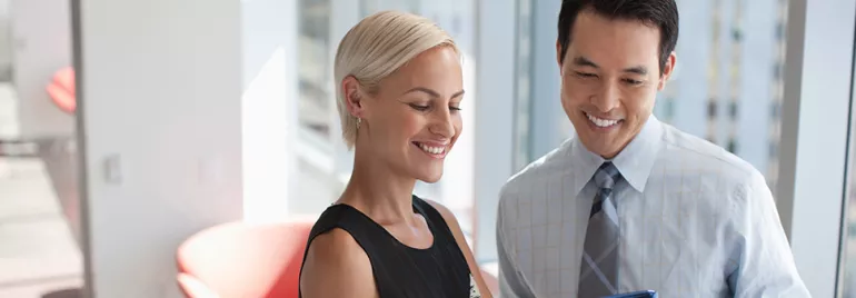 Two colleagues discussing documents in a bright office.