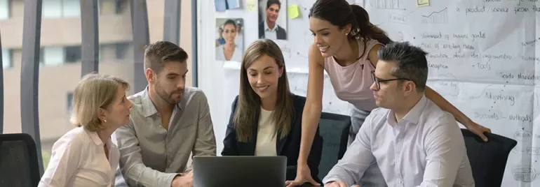 Group of professionals discussing a project around a laptop in a modern office.