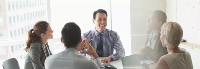 Business meeting with diverse team smiling around a conference table.