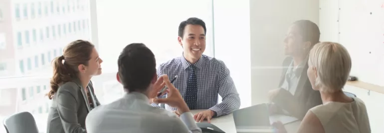 Business meeting with diverse team smiling around a conference table.