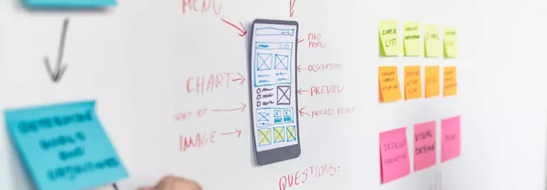 Whiteboard with UI/UX design sketches and color-coded sticky notes.