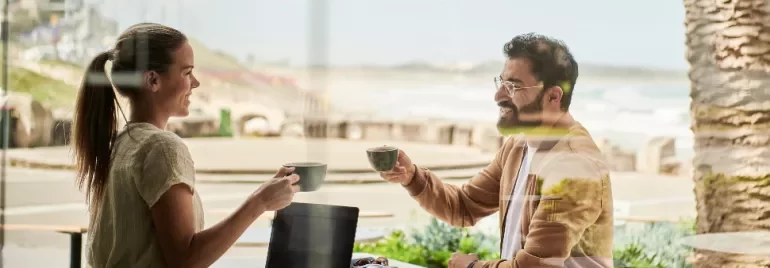 Two people enjoying coffee and conversation at a beachside cafÃ©.