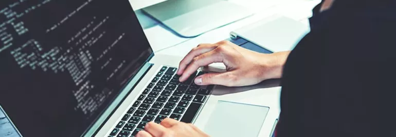 Person typing on a laptop with code displayed on the screen.