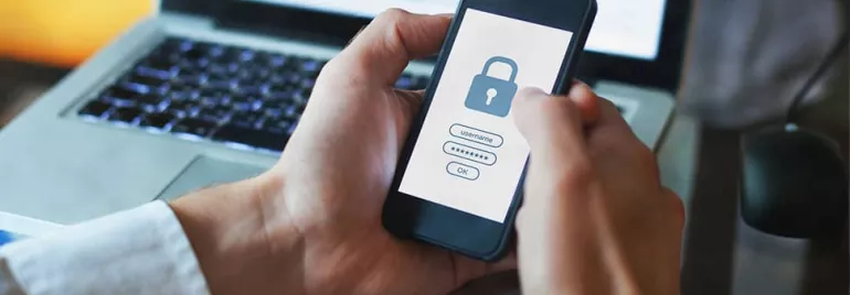 Person uses smartphone for secure login with a lock icon on the screen.