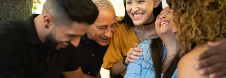 Group of diverse people smiling and hugging each other closely.