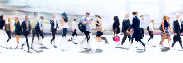 Blurred image of people walking on a busy city street.