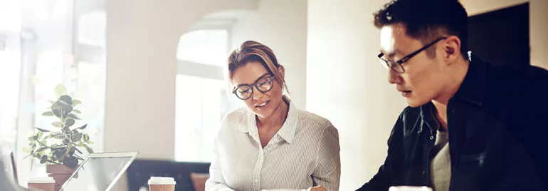 Two people collaborating over coffee in a bright office setting.