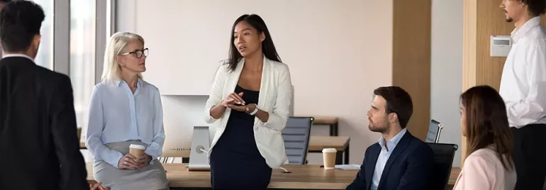Businesswoman leading a discussion with colleagues in a modern office.