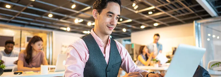 Man at laptop in modern office setting.