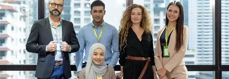 A diverse group of five people smiling in a modern office setting.