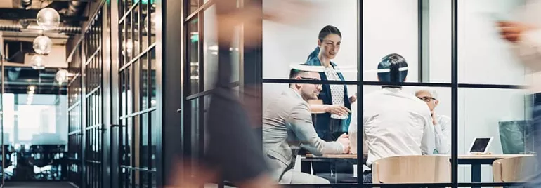 People in a glass-walled conference room having a meeting.