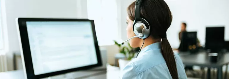 Person in a headset working at a computer in an office.