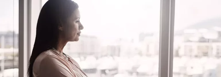 A woman gazing thoughtfully out of a window.
