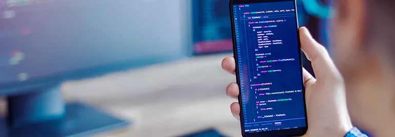 Person holding a smartphone with code visible on the screen.