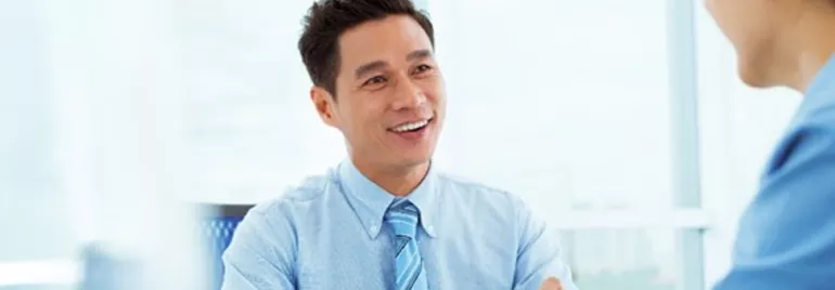 Man in a blue shirt smiling during a meeting.