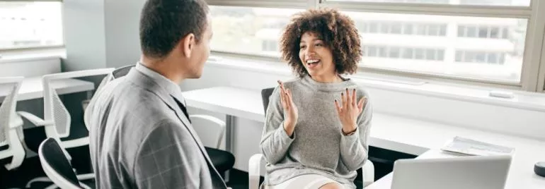 Two colleagues having a cheerful discussion in a modern office.