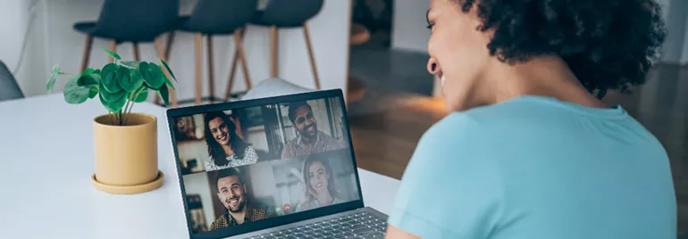 Person in a blue shirt on a video call with four people on their laptop.