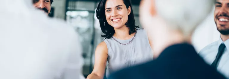 Smiling woman shaking hands in a group meeting.