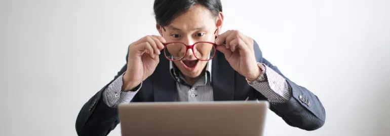 Excited man looking at laptop screen with surprise.