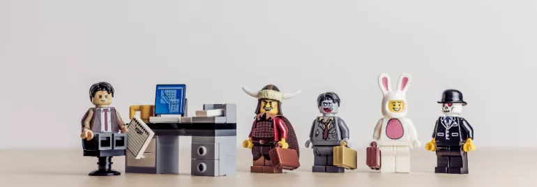 Lego minifigures in costume line up in an office setting.