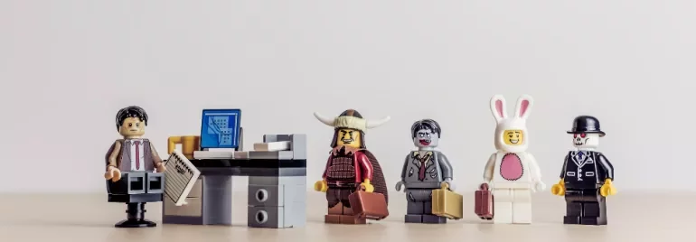Lego minifigures in costume line up in an office setting.